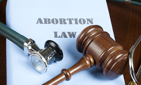 Gavel and stethoscope on briefing paper with "Abortion law" written on it