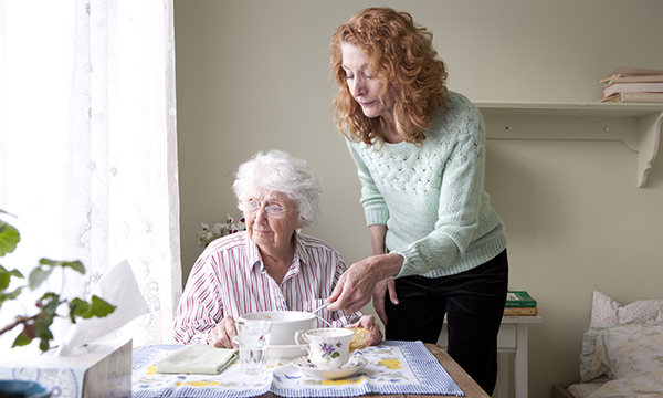 middle-aged woman helps older women with breakfast