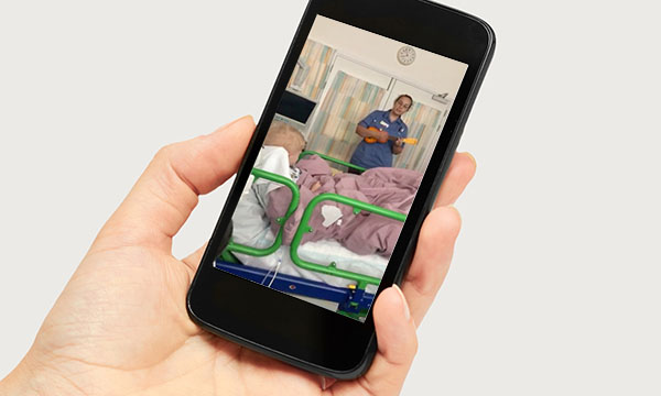 Hand holds phone showing video of singing nurse Beth Porch at Great Ormond Street Hospital