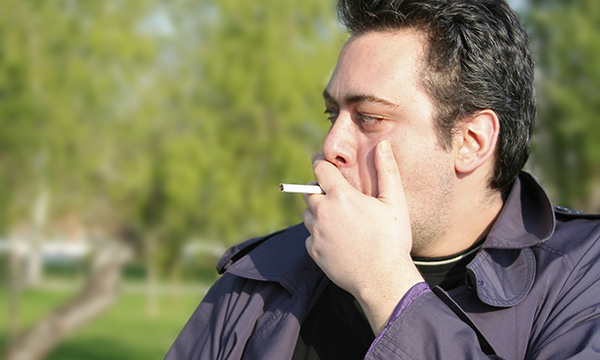 man standing outside, smoking. A hospital trust has banned smoking on its site, even outdoors