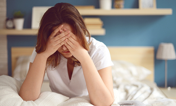 woman sits with her head in her hands, as NHS reveals stress and depression are main causes of sickness absence