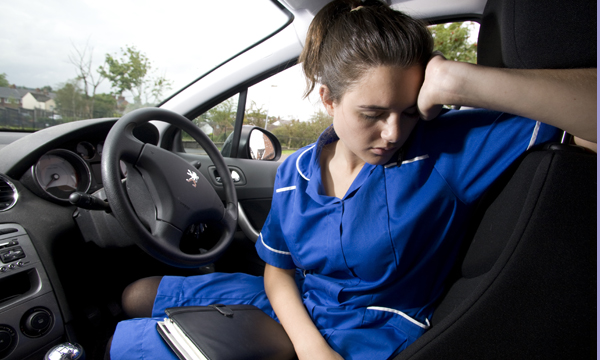 exhausted community nurse sits slumped in her car