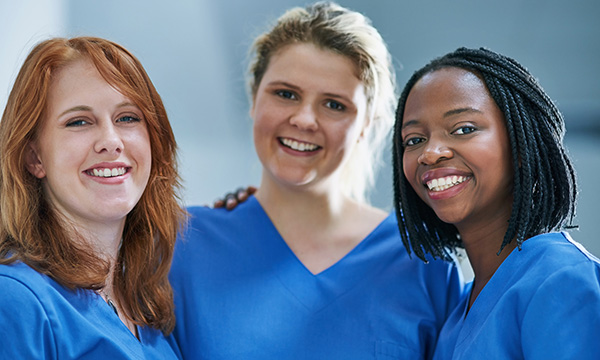 three nurses, dressed in identical uniforms, smiling