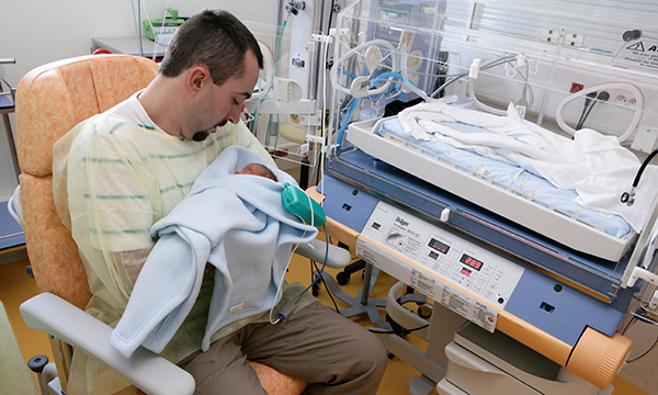 Picture shows a father holding a baby in a neonatal unit. This editorial says parents need more support when infants go into neonatal care, but proposals in the latest consultation fall short.