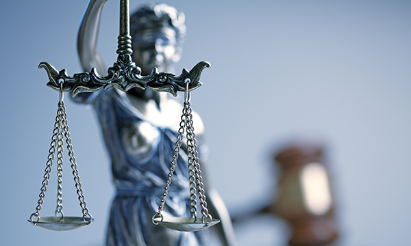 Scales of justice in the foreground, a gavel in the background