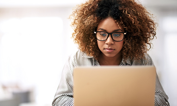Picture shows a young woman looking at a screen. Nurses are urged to share stories of front-line care delivery in an RCN survey.