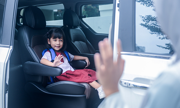 Child strapped into car seat waves to adult who will be left behind