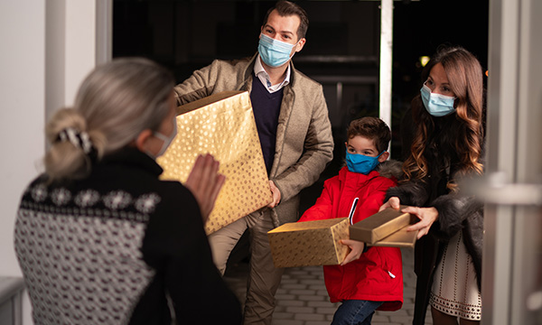 Picture shows a young couple and child offering gifts to an older woman
