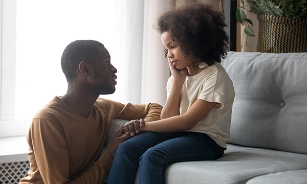 Man sits on floor next to child, both are looking sad