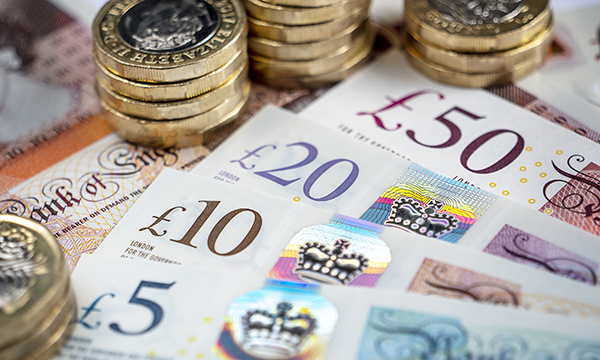Picture shows piles of £1 coins and assorted UK bank notes.