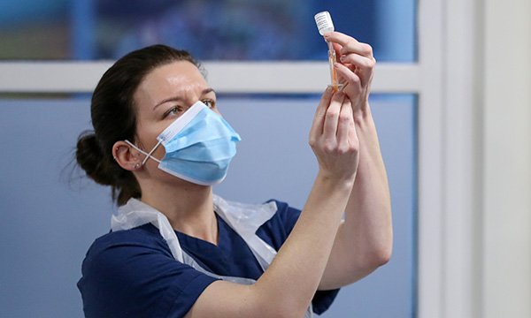 nurse prepares a vial of coronavirus vaccine as staff are urged to have the jab 