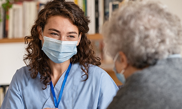 social care worker wearing face mask has a conversation with a client