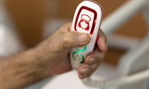 hand holding call bell featuring 'nurses' symbol depicting woman in a starched cap