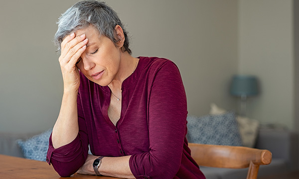 woman slumps with head in hands – fatigue is a symptom of long-COVID