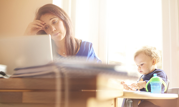 woman looks despondent, with child in high chair by her side – study suggests many children of nurses and other key workers live in poverty