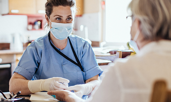 district nurse carries out a finger prick test in patient's home