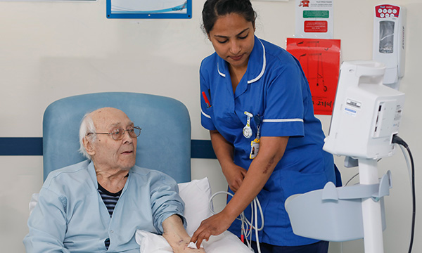 A nurse of Asian heritage looking after a hospital patient