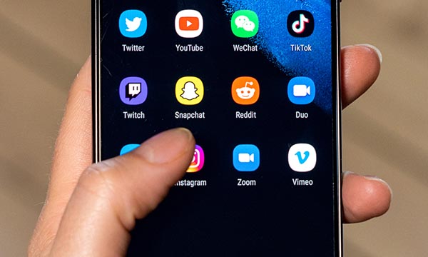 Picture shows someone holding a smartphone and pressing the Snapchat app