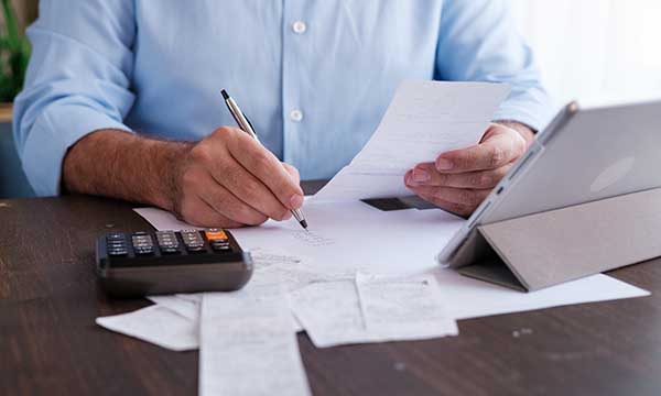 A man sitting at a desk with several papers and making notes
