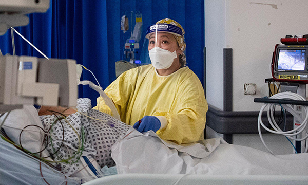 Nurse wearing PPE at patient’s bedside in ICU at St George’s Hospital in London during the COVID-19 pandemic