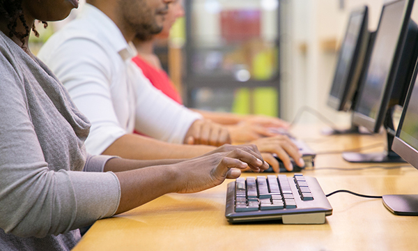 People at a desk doing a computer-based test of competence programme
