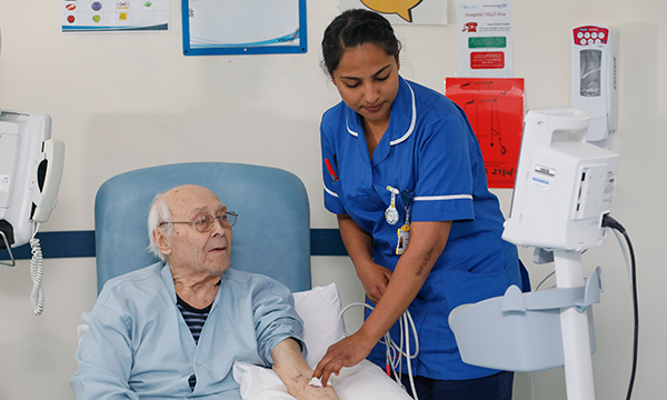 Photo of overseas nurse with patient, illustrating story about rise in overseas recruits