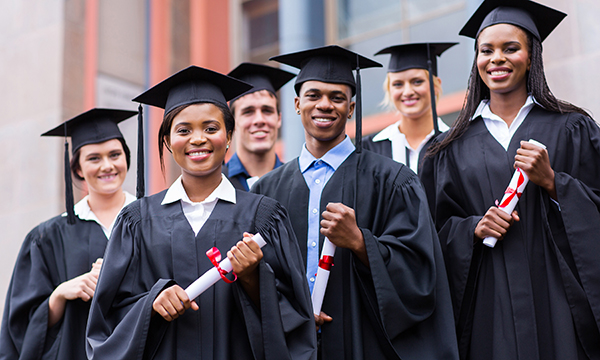 Young graduates standing in front of university building on graduation day