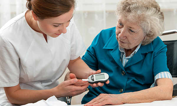 A nurses uses a blood glucose monitor on an older person: diabetes management can fall through the gaps when older people transfer to care homes