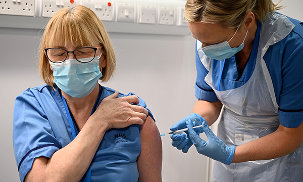 Grace Thomson (left) receives a COVID-19 vaccination from fellow nurse Paula McMahon at the NHS Louisa Jordan Hospital in Glasgow in December 2020 on the first day of the largest immunisation programme in the UK's history