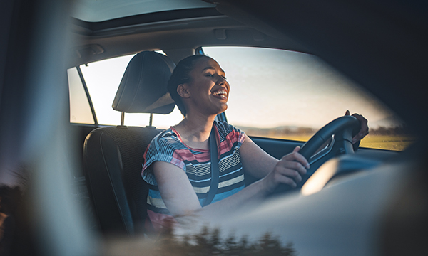 A happy woman at the wheel of a car singing along to music