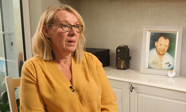 Elaine Clarke sitting in her home next to a picture of her brother, Clive Treacey