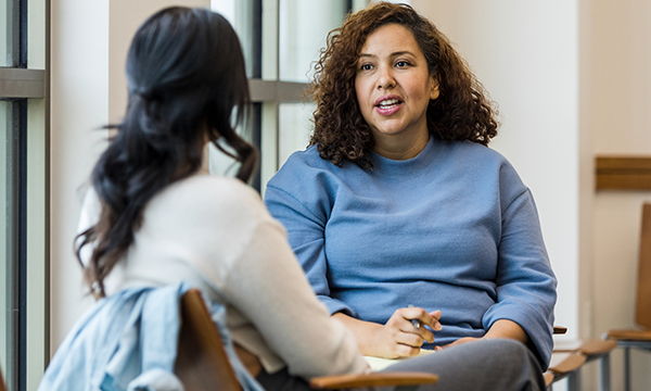 A mental health nurse taking notes and talking to a patient sitting next to her