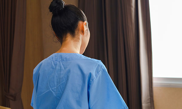 Nurse with her back to the camera appears to feel isolated as union and care sector call on government to act against exploitation of foreign care staff in the UK