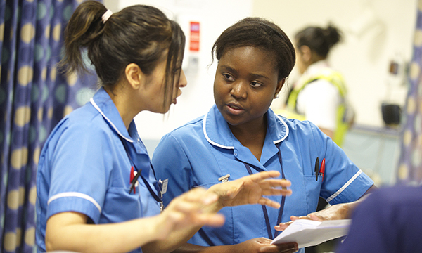 Two nurses in discussion about a document one of them is holding