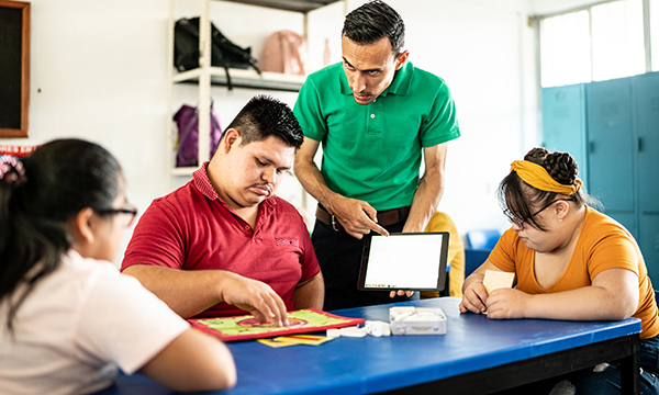 A nurse-educator shows a small group of young people with learning disabilities a website on his tablet computer about intimacy and relationships