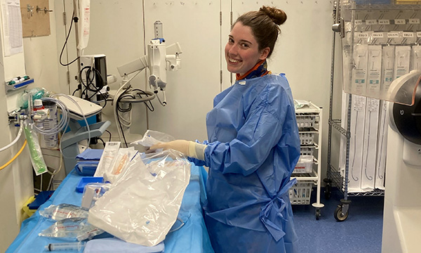 Article author and newly registered nurse Alice Amil smiles as she arranges equipment in the cath lab