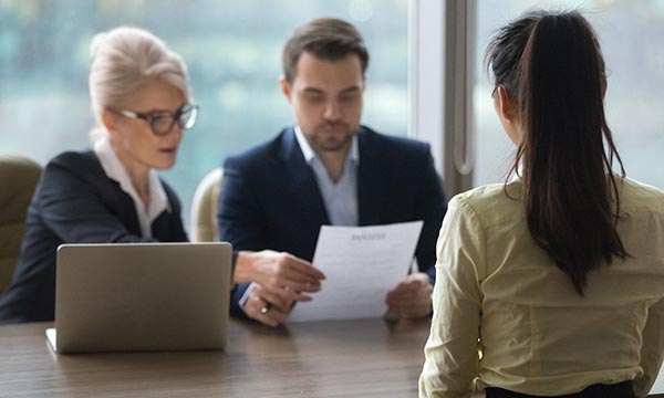 A tribunal panel looks as documents, with witness facing them across a table. A nurse with Chron’s disease won a tribunal after NHS employer reneged on reasonable adjustments