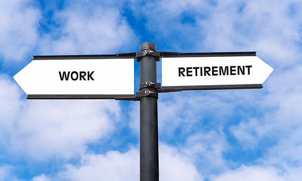 Road sign post seen against a blue and cloudy sky. The sign points in opposite directions: work to the left, retirement to the right. Changes in NHS pension rules mean some nurses are choosing to return to practice, even in retirement