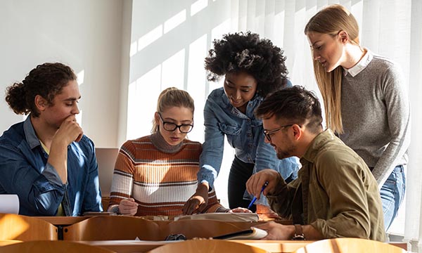 Group of young people in a huddle as if planning how to execute a task, illustrating group work in nursing education
