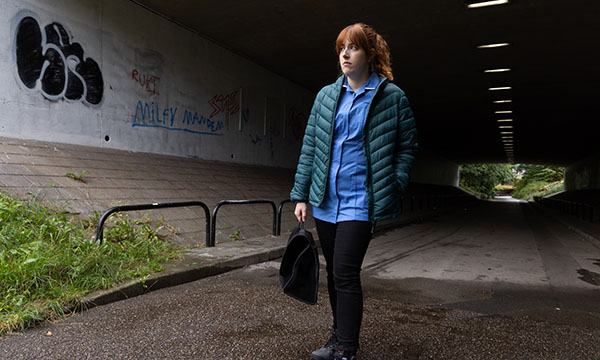 A community nurse looks apprehensive as she emerges into the daylight from a long, dark pedestrian tunnel 