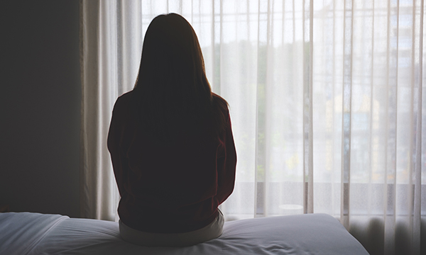 Person in shadow looking out of window, illustrating story about nurse and midwife suicides