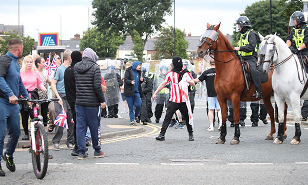 Filipino nurses targeted in Sunderland riots: a man in a mask stands stands next to a police horse as riot police confront protestors in the city centre on Friday