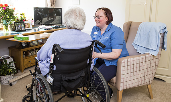 SceA nurse chats with an older woman in a wheelchair. With more people choosing to receive care close to home, the role of nursing professionals will become increasingly vital.