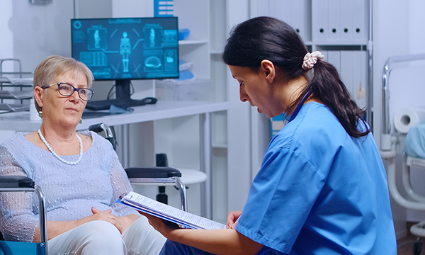 A nurse looks at a document while in discussion with a female patient. It is hoped that new profiles will more accurately reflect the reality of present-day advanced nursing skills, training and practice