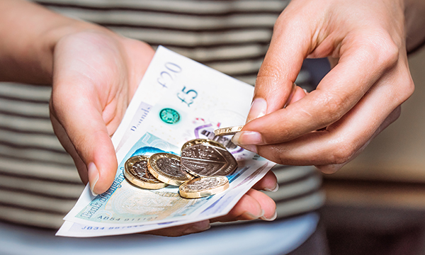 Nursing students facing money worries: someone counting cash in their hands, including a £20 note, a £5 note and five £1 coins