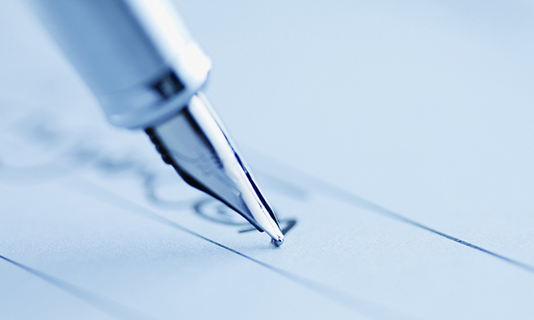 Photo of pen writing on paper, illustrating story about a nurse investigated after signing off on competencies that required a supervisor's signature