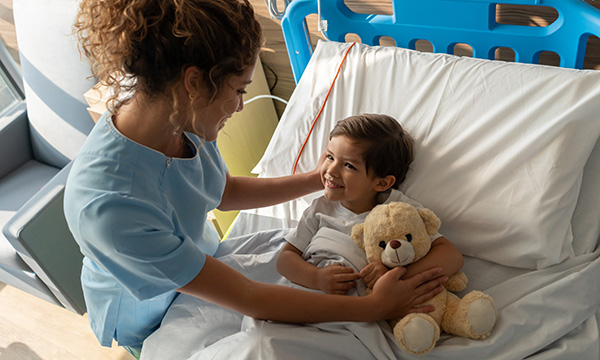 Children’s hospice care: children are living longer, with more complexity and technology dependence than ever before: a nurse comforts a child with a teddy bear in a hospice bed