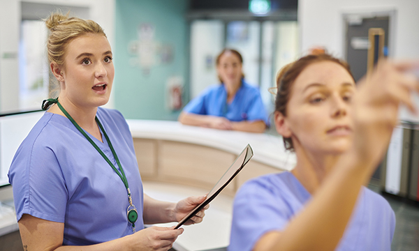 Streamlined handover process: a nurse watches a colleague write a patient’s details up on the board on a hospital ward