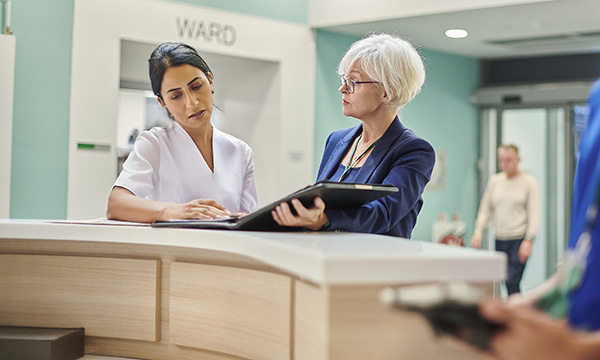 Regulation of NHS managers: an NHS manager speaks to a staff member at a hospital nurses station