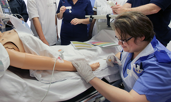 Simulated clinical nursing skills training: a nurse practises taking blood on a manikin in a clinical training session